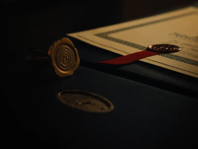 Brass seal stamp beside an embossed certificate on a dark desk